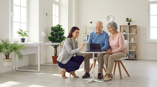 A tech professional helping a senior with a device in a bright home setting.